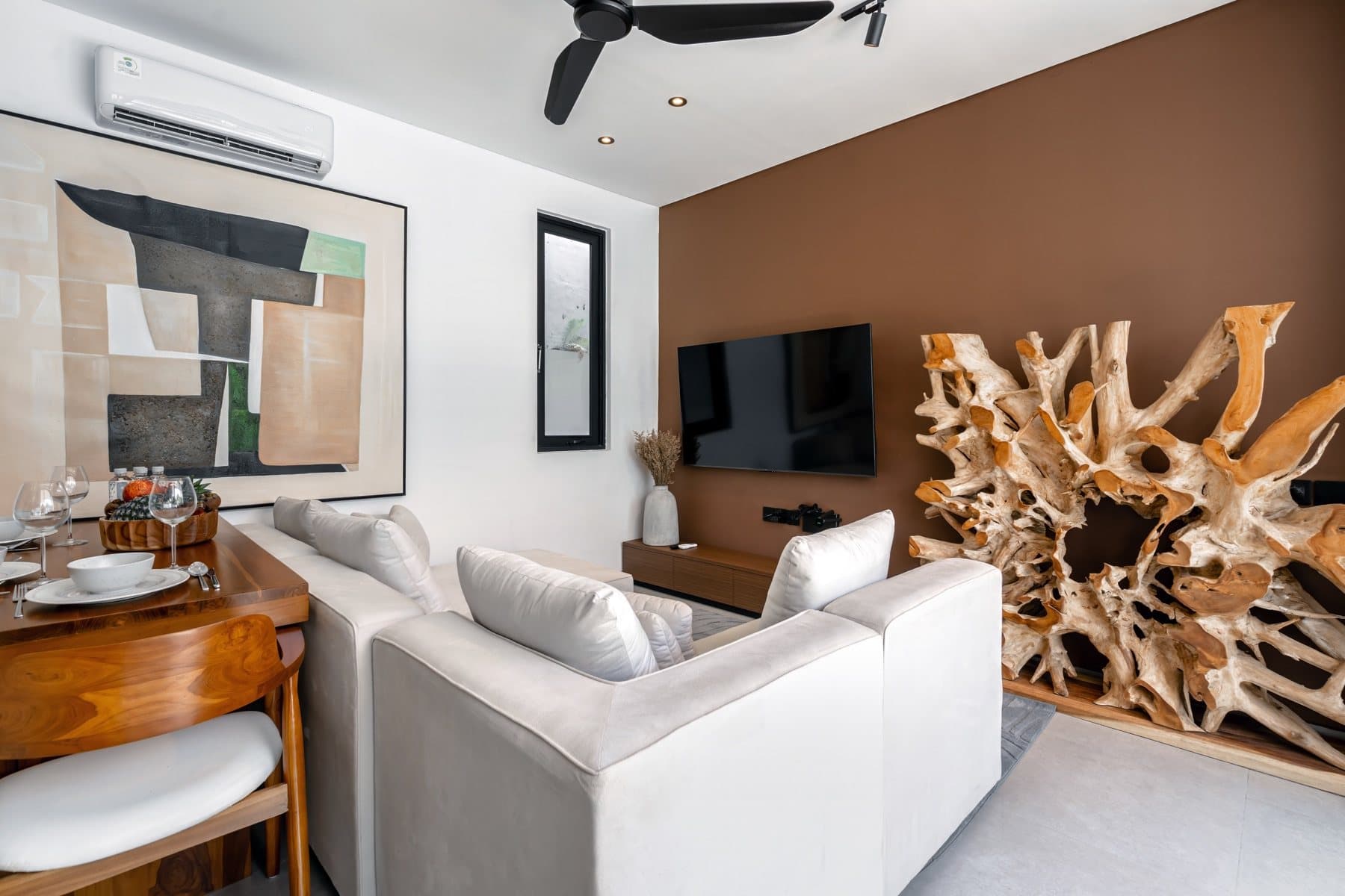 Furnished living room with a sofa, television and sculptural wooden decor
